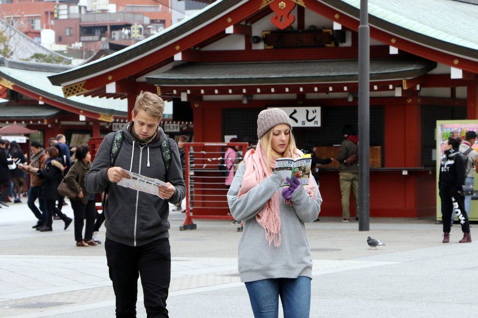 This picture taken on 3 March 2015 shows foreign tourists looking at a guide book and a map at Sensoji temple at Tokyo's Asakusa district