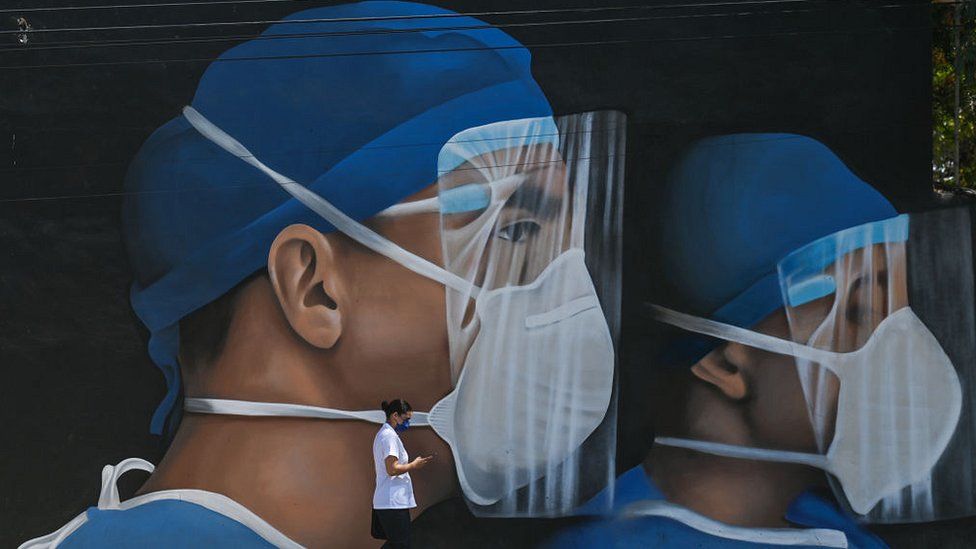 мужчина проходит мимо фрески с изображением медицинских работников в СИЗ
