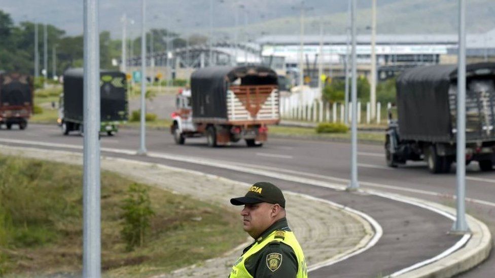 Lorries with humanitarian aid drive past a Colombian policeman to the Tienditas Bridge on the border between Colombia and Venezuela. Photo: 7 February 2019
