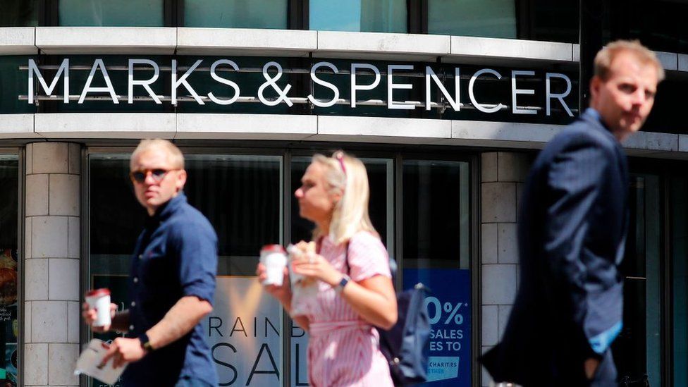Shoppers walk past M&S in central London