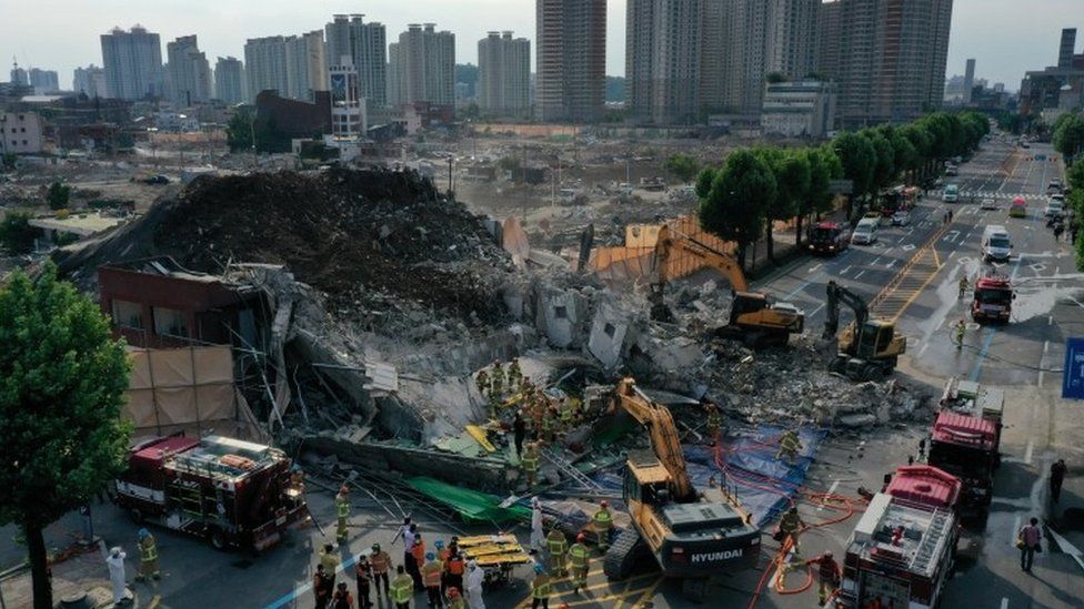 South Korean firefighters search for passengers from a bus trapped by the debris of a collapsed building in Gwangju