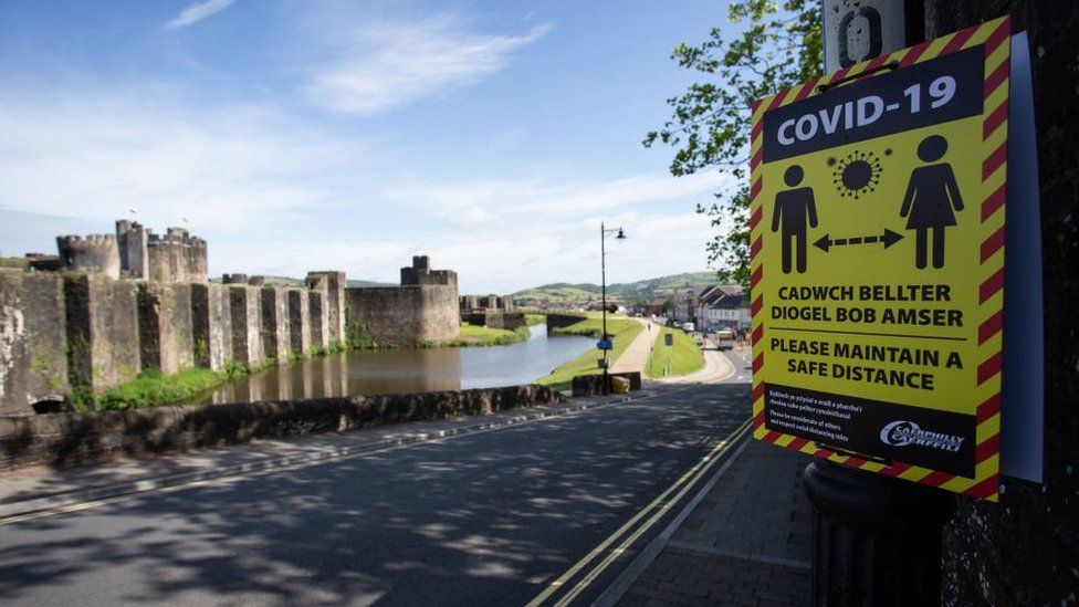 A Covid-19 poster in the foreground with Caerphilly Castle in the background
