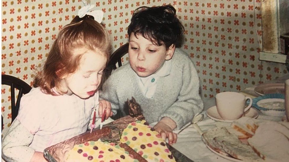 Timothy blowing out a birthday cake with his sister