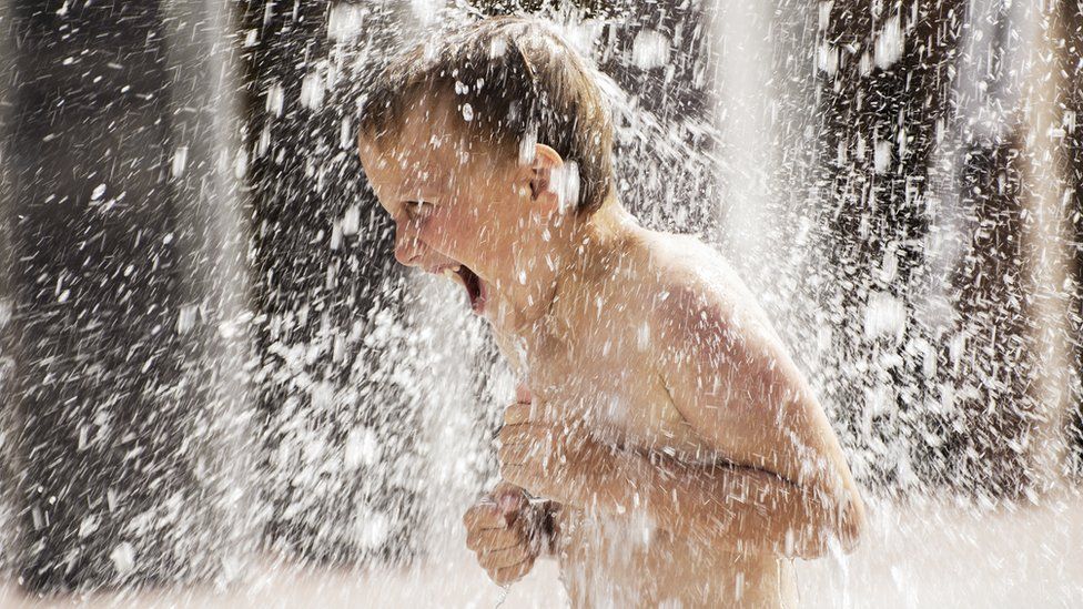 A young boy laughing under a water spray