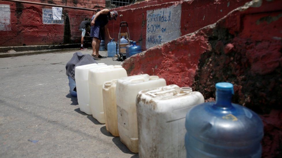 A man fills plastic containers with water from a pipe in a street of a slum during a nationwide quarantine due to coronavirus disease (COVID-19) outbreak in Caracas, Venezuela April 2, 2020