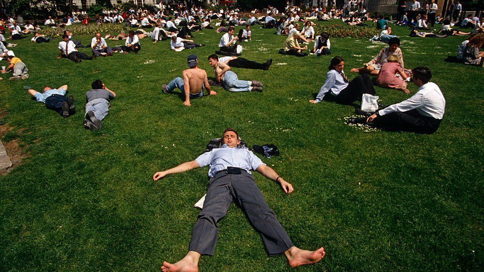 Office workers enjoy the midday sun in Trinity Square in the City of London during the UK's summer heatwave.