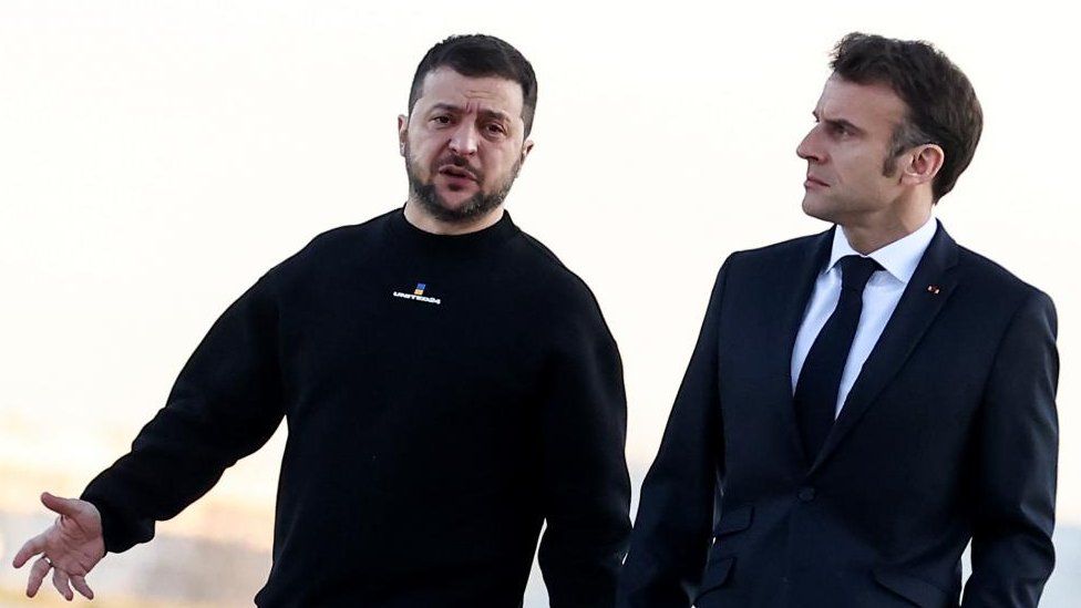 French President Emmanuel Macron (R) walks next to Ukraine's President Volodymyr Zelensky (L) before heading to Brussels, in Military Airport Villacoublay, in Velizy-Villacoublay, Southwest of Paris