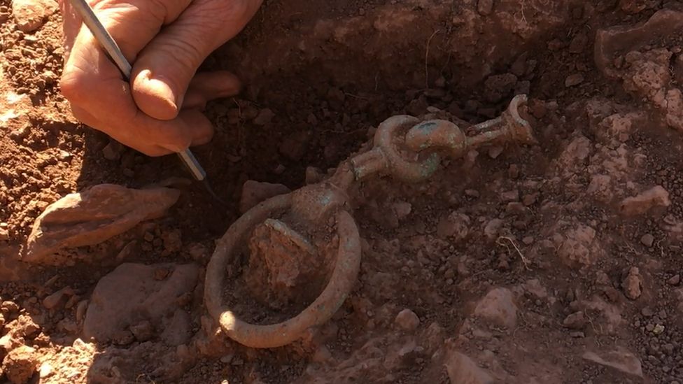 Photo of a bridle bit being unearthed