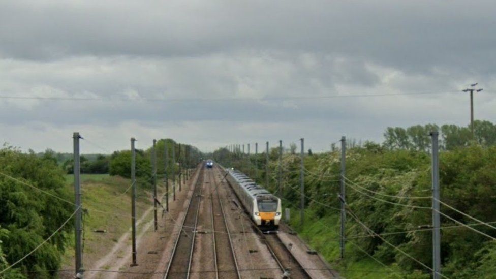 Three-line stretch of mainline railway with two trains visible