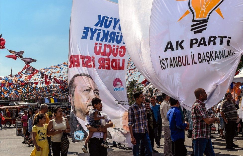 People hold an election poster showing Turkey's president and the banner of the ruling Justice and Development Party (AKP) during a rally in the Eminonu district of Istanbul on June 14, 2018.