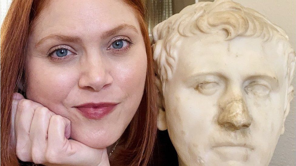 Woman poses with Roman bust