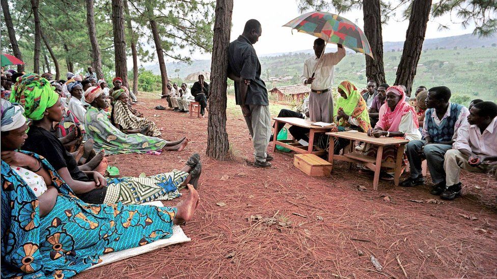 A picture taken 03 December 2003 shows a witness facing the president (with umbrella) of a gacaca court session in Rukira, during a hearing in relation with the 1994 Rwandan genocide.