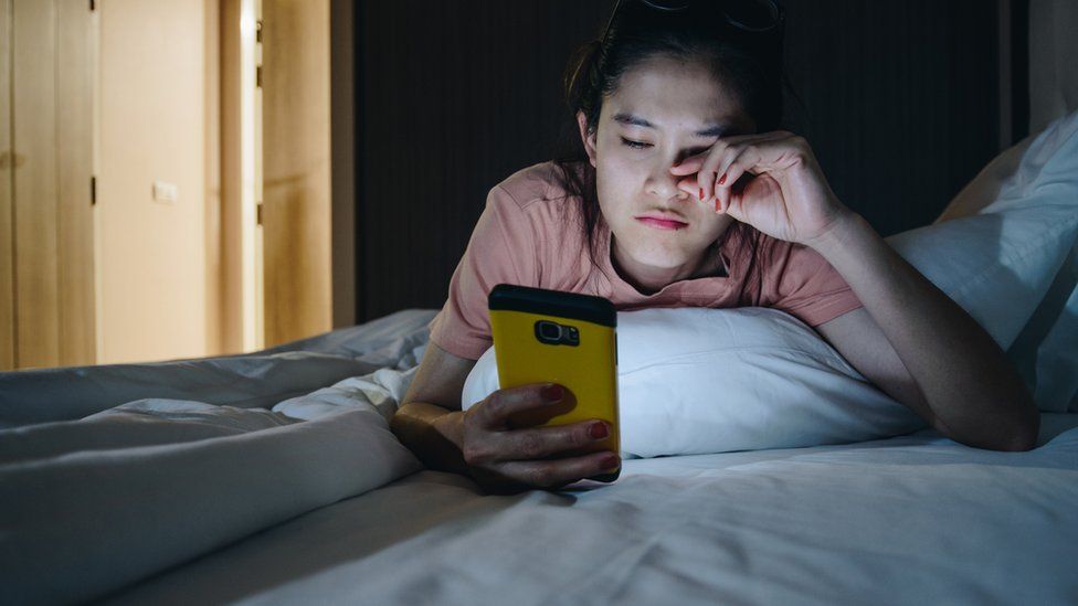Young woman looking at her phone at night