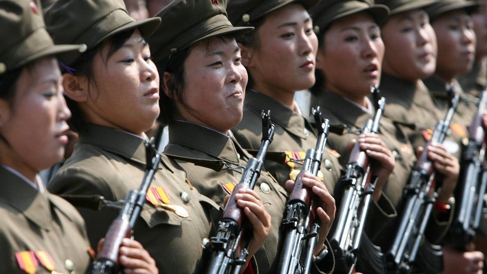 A row of female officers with guns and caps