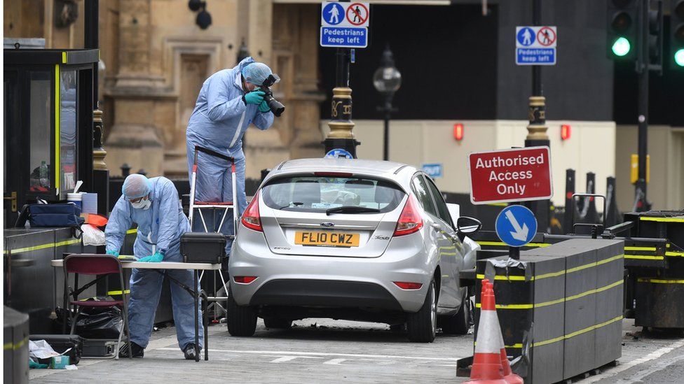 Forensic officers by the car that crashed into security barriers outside the Houses of Parliament, Westminster, London.