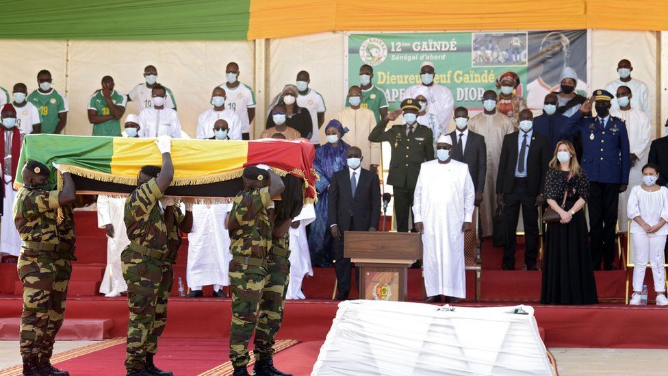Senegal's president Macky Sall (C) and the widow of Papa Bouba Diop, Marion Diop attend a ceremony marking the reception of the coffin of former international Papa Bouba Diop