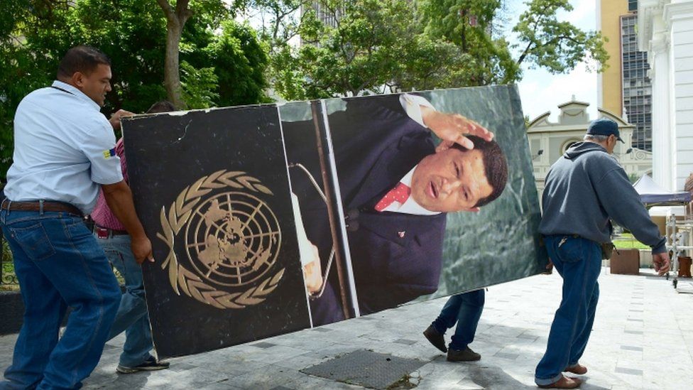 National Assembly employees remove from the building pictures of late President Hugo Chavez, in Caracas on January 6, 2016.