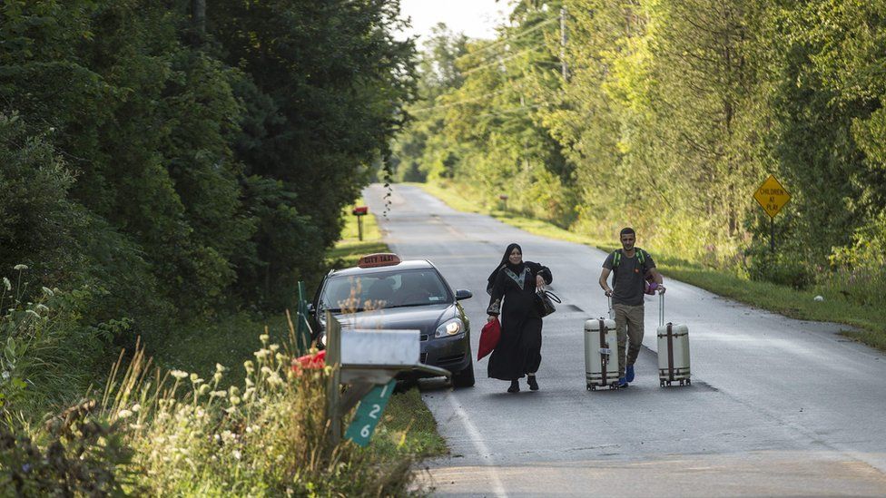 A cab drops off a couple of asylum seekers at the US/Canada border near Champlain, New York