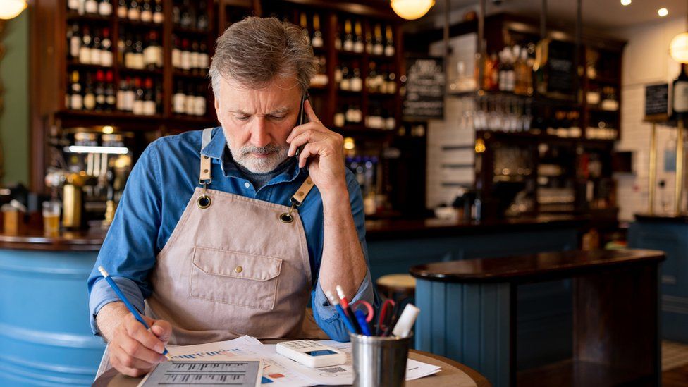 Business owner talking on the phone while working on the accountancy at a restaurant - Small business concepts