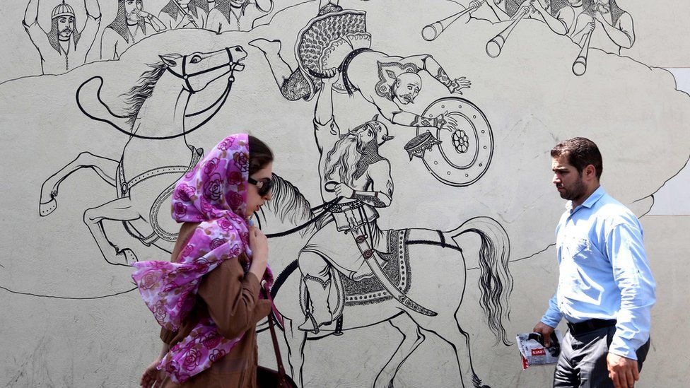 People walk past a mural in Tehran, Iran (25 June 2019)