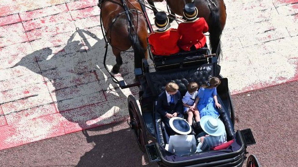 Catherine, Duchess of Cambridge, her children Prince Louis of Cambridge, Prince George of Cambridge, Princess Charlotte of Cambridge, and Camilla, Duchess of Cornwall travel in a horse-drawn carriag
