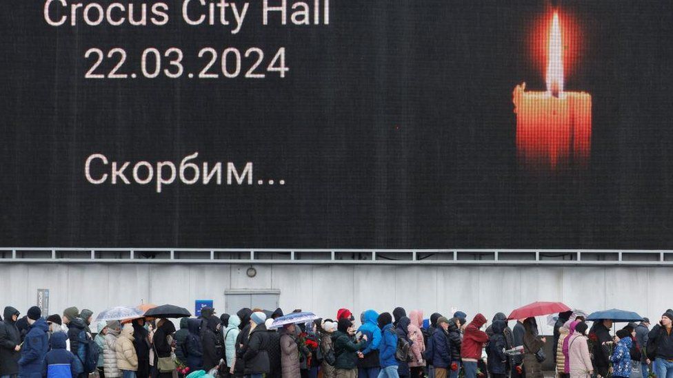 People queue to lay flowers at a makeshift memorial to the victims of a shooting attack set up outside the Crocus City Hall concert venue in the Moscow Region, Russia, March 24, 2024.