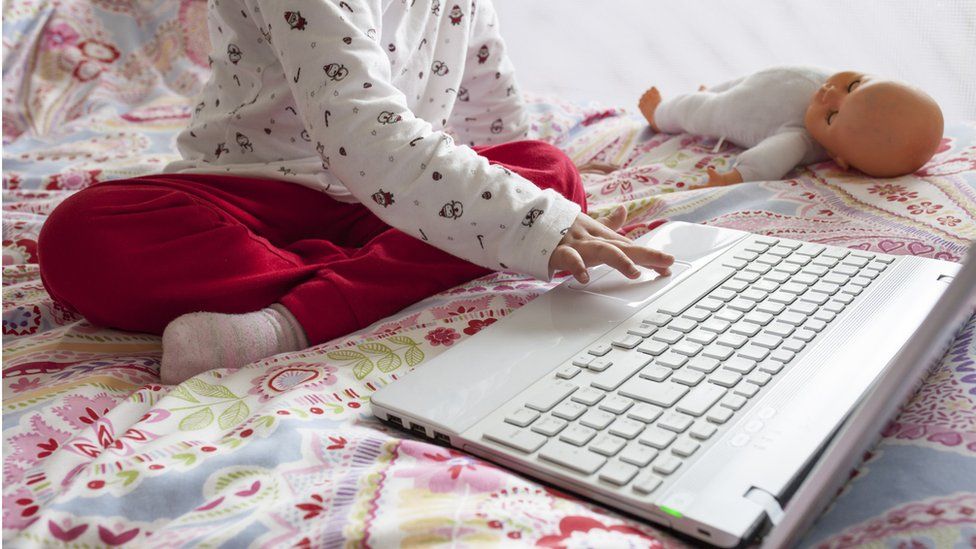 A child sitting in bed with laptop
