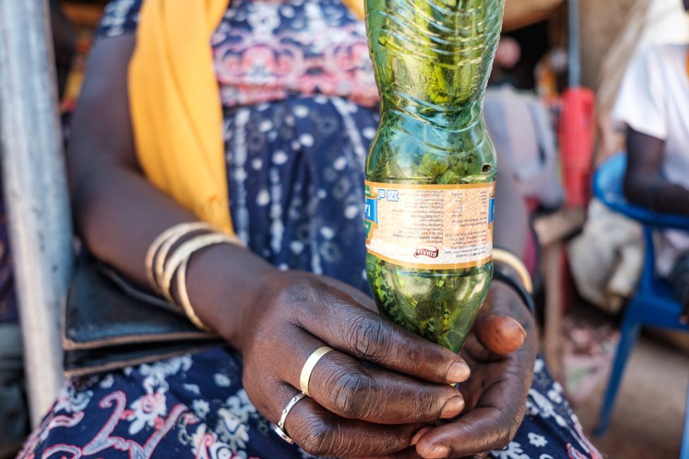 A woman holds a plastic bottle filled with locusts
