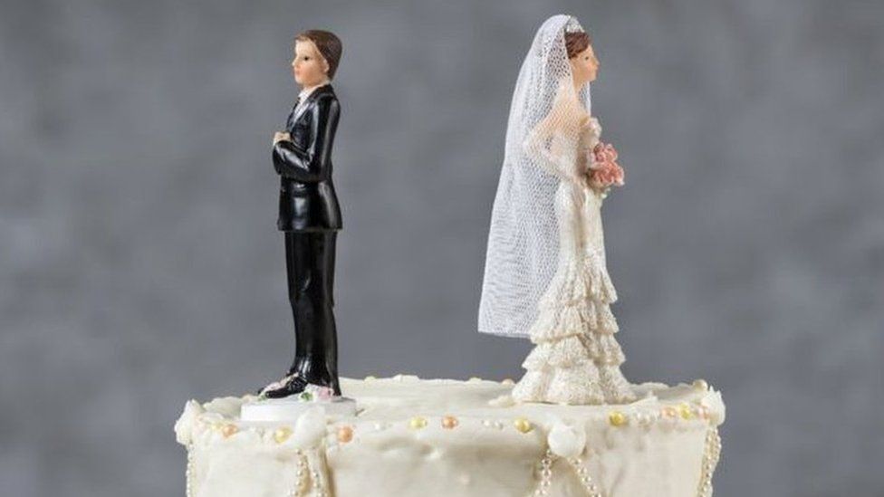 Cake toppers facing away from each other on a wedding cake