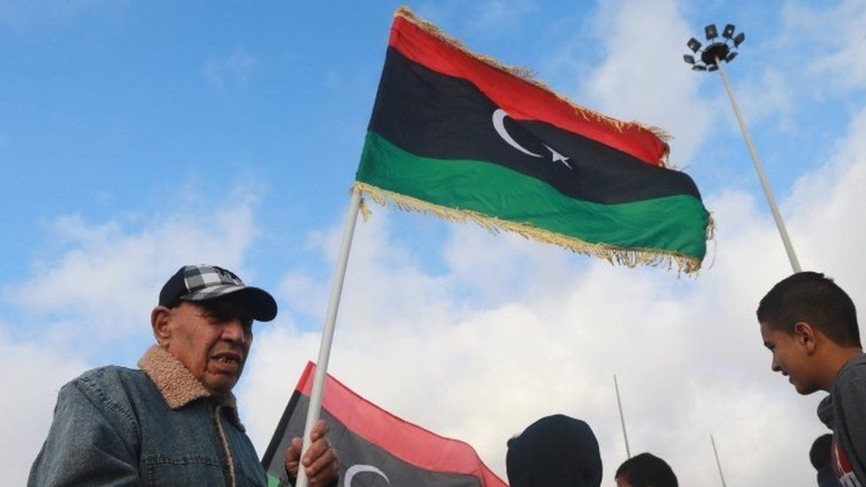 A man in Benghazi waves the national flag as he celebrates gains made by Libya's eastern government (21 February 2016)