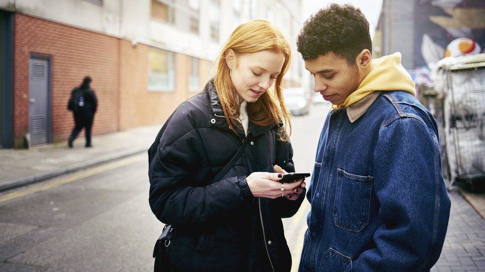 Young people looking at mobile in the street
