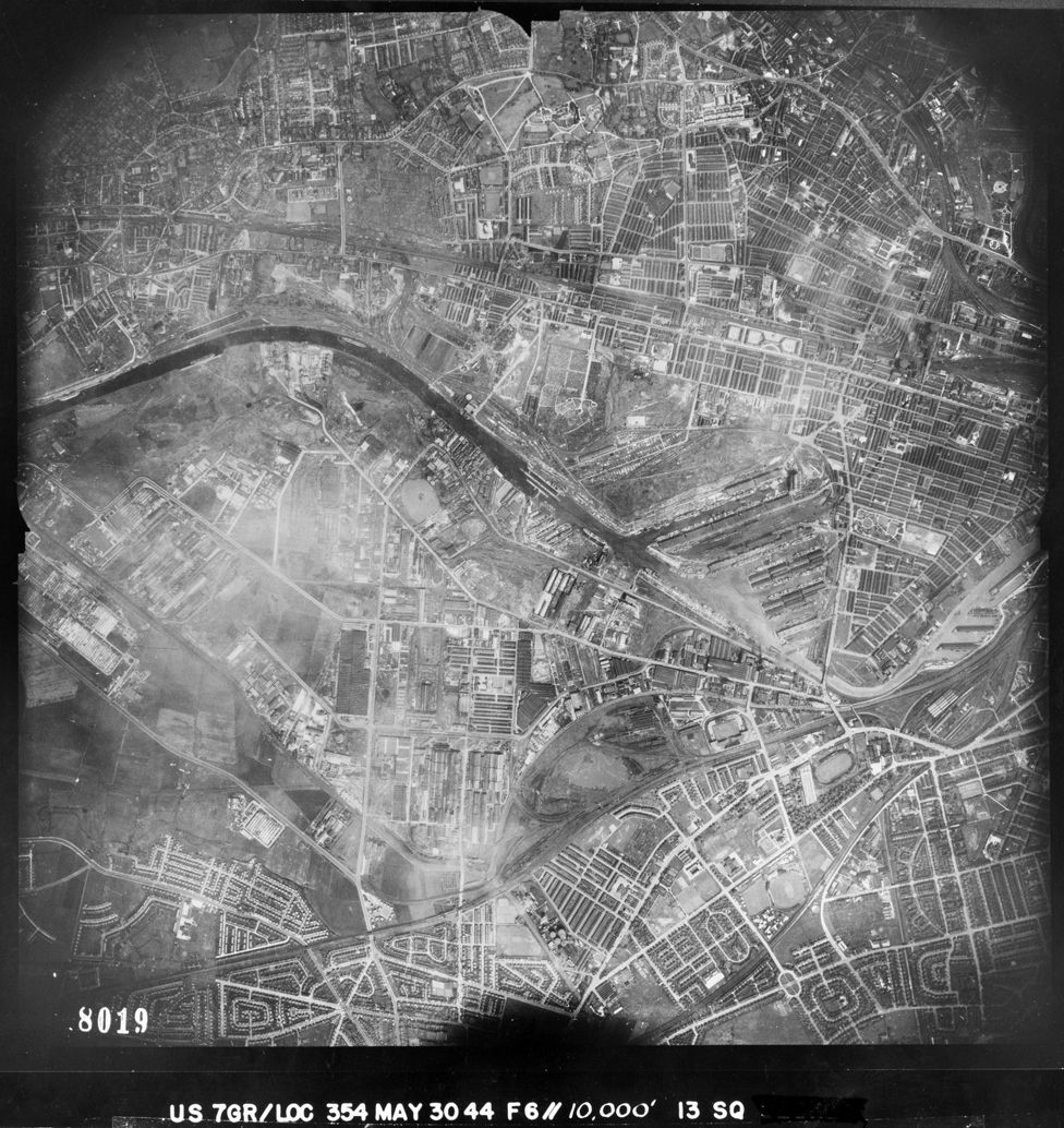 An aerial view of Salford showing the Manchester Ship Canal and Salford Docks. Bottom-right are Old Trafford football and cricket grounds and White City stadium