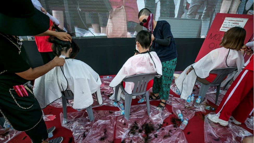 Women shaving their heads at a public protest