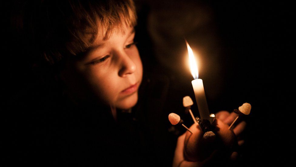 Boy focussed on Christingle Orange with candle during Christian Advent celebration