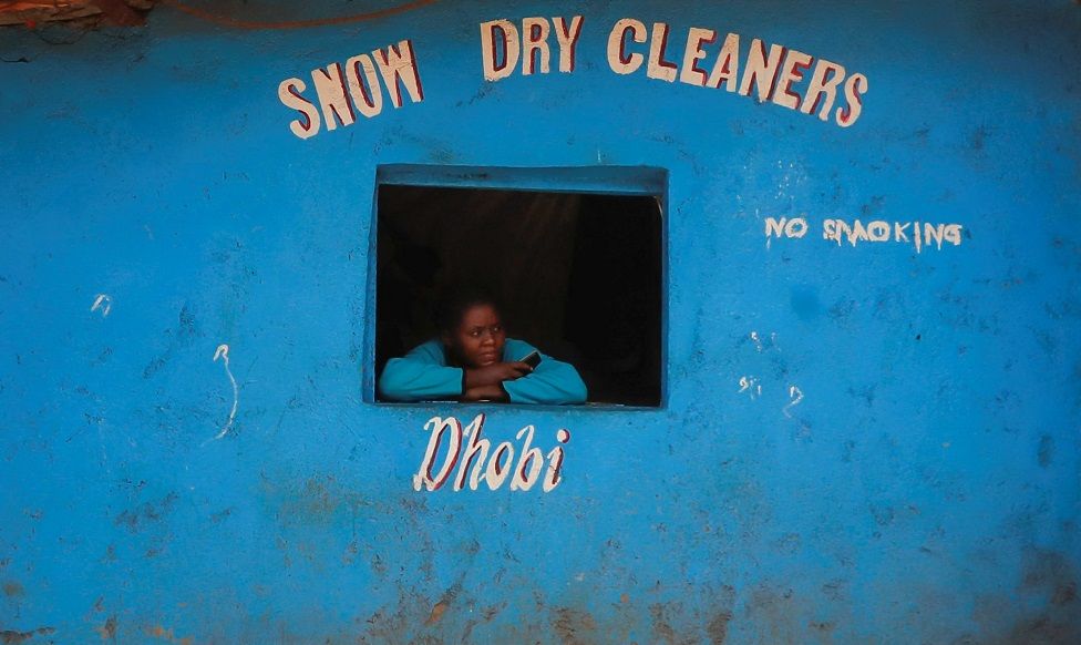 A woman looks from the window of a laundry service in the Kibera neighbourhood of Nairobi.