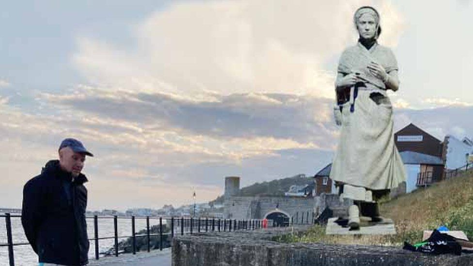 Model of Mary Anning statue superimposed on a photo of the location next to a footpath beside the sea