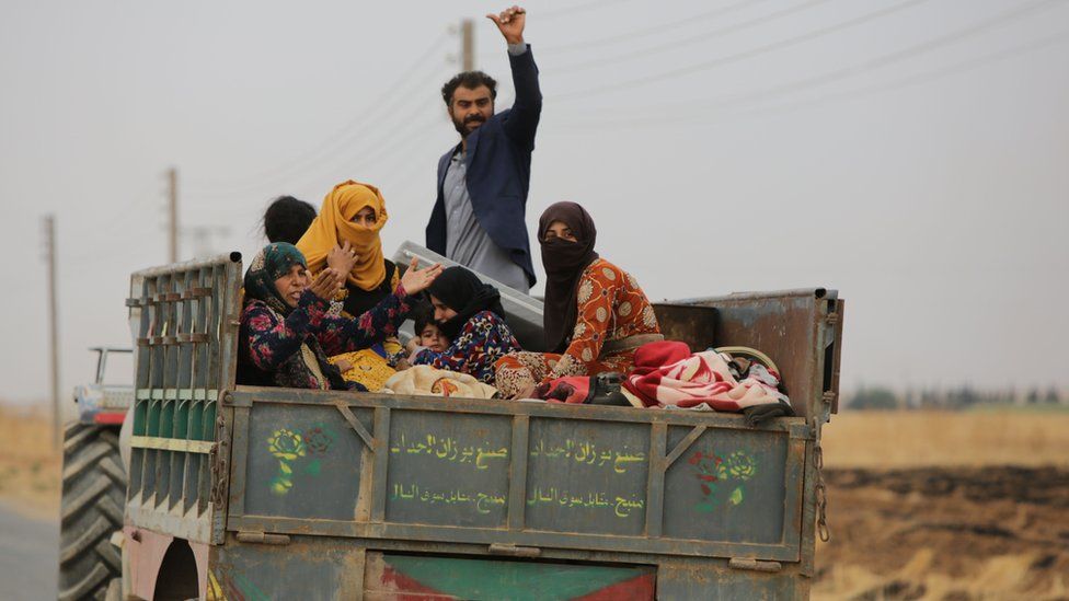 Syrian civilians ride in the back of a trailer as they flee the countryside around Tal Abyad, northern Syria (24 October 2019)