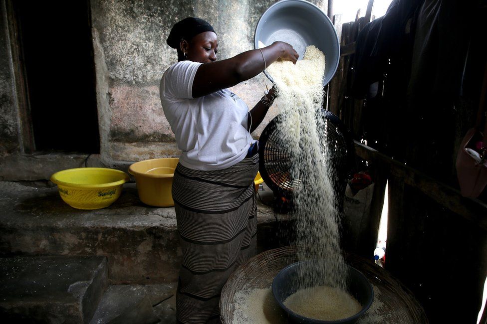 A woman holds up a bowl as she prepares Cassava flour on 21 July 2023.