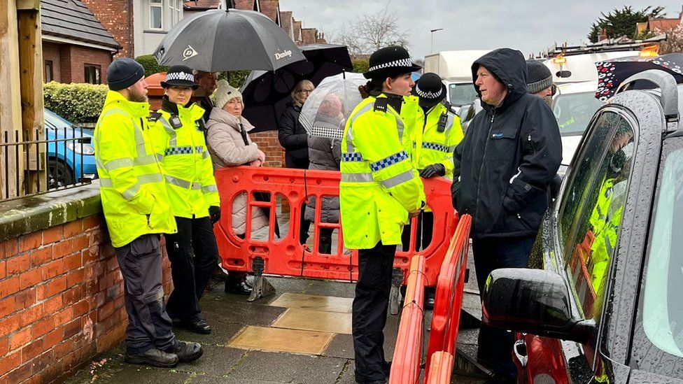 Police in attendance as residents blockade a road in Southport as part of their protest against the installation of telegraph poles