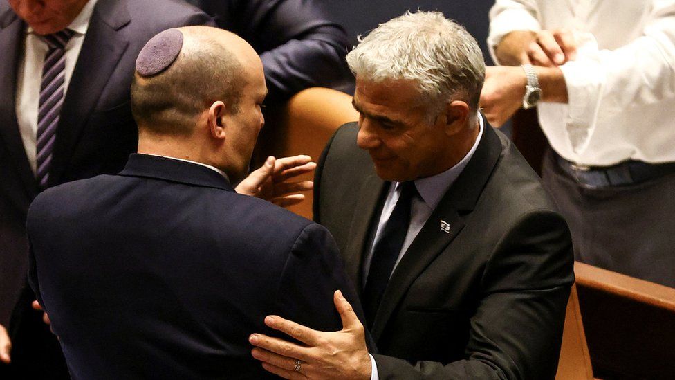Naftali Bennett (L) embraces Yair Lapid (R) after Israel's parliament votes to dissolve itself and Mr Lapid is named interim prime minister (30 June 2022)