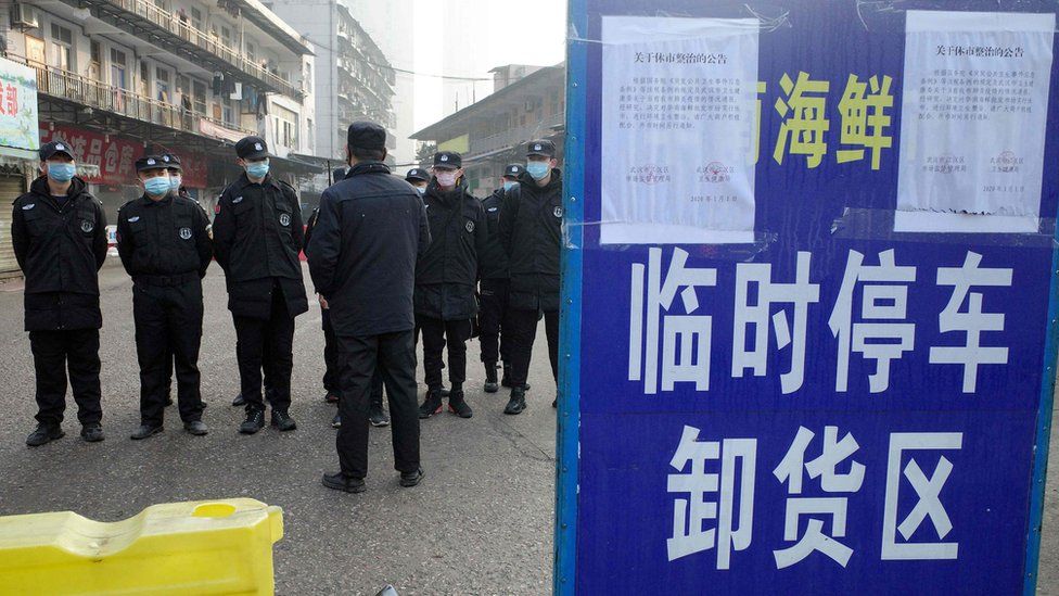 Security guards stand in front of a closed seafood market in Wuhan, which has been linked to the outbreak