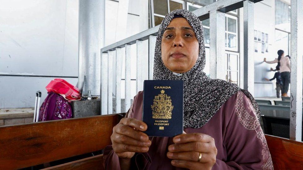 Palestinian-Canadian Seham al-Batnejy displays her passport as she waits at Rafah border crossing after evacuations were suspended following an Israeli strike on an ambulance, in Rafah in the southern Gaza Strip