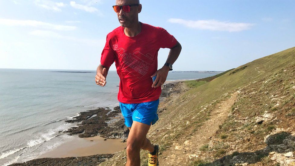 Phil Young running along a coastal cliff path
