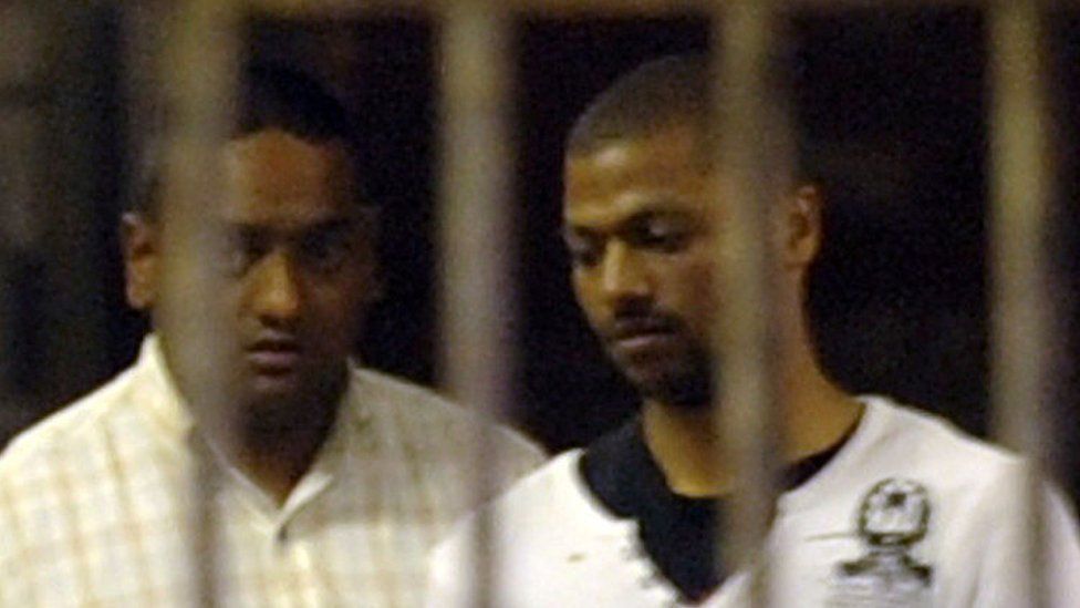 A police officer leads Thabo Bester (right) out of the holding cells at the Durban Magistrates Court on October 12, 2011