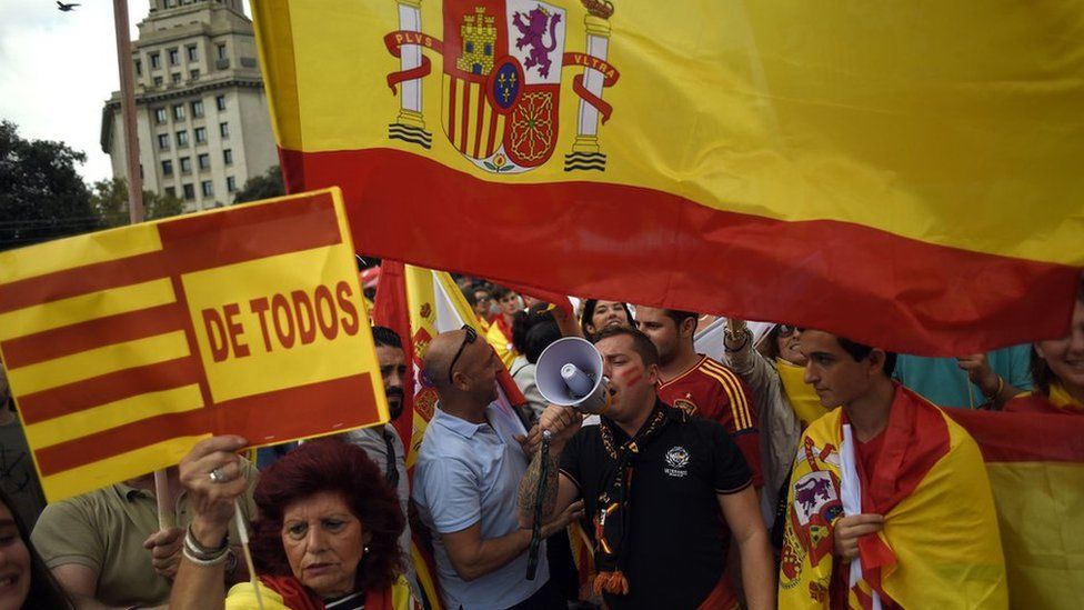 Protesters wave Spanish and Catalan flags during a demonstration called by Catalan Civil Society under the motto "Catalonia yes, Spain too" in Barcelona on October 12, 2017.