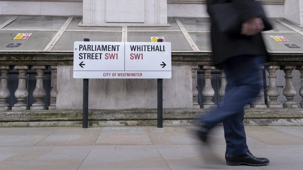 Man walking next to Whitehall sign