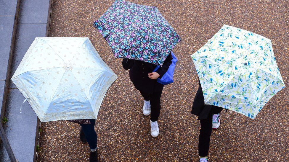 People with umbrellas during May rainfall