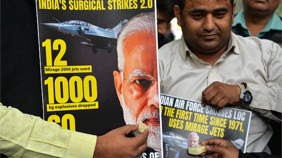 Supporters of Indian Prime Minister Narendra Modi offer sweets to a poster displaying his portrait in New Delhi on February 26, 2019, as they celebrate the Indian Air Force (IAF) strike launched on a Jaish-e-Mohammad (JeM) camp at Balakot.