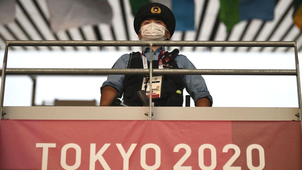 Перед открытием наблюдает сотрудник службы безопасности Церемония Олимпийских игр 2020 года в Токио 23 июля 2021 года.