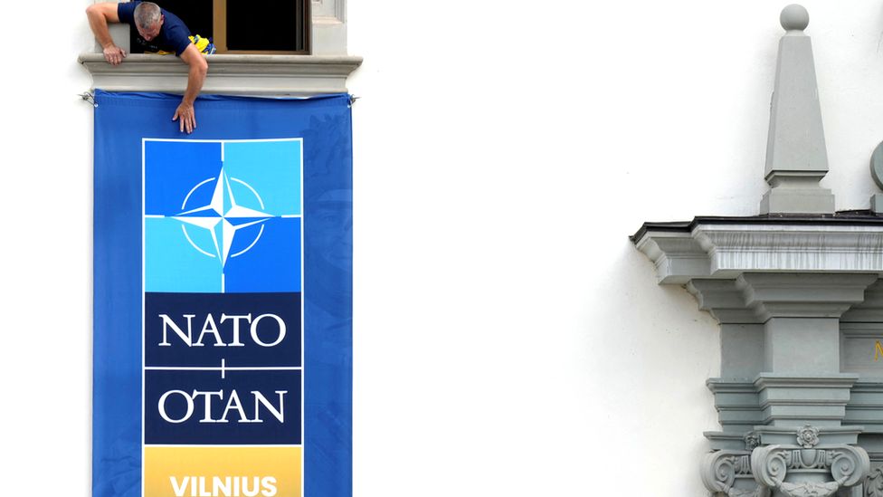 A man hangs a banner for the Nato summit in Vilnius